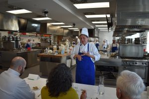 Participant discuses her dish to a panel of judges