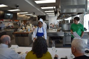 Participant discuses her dish to a panel of judges
